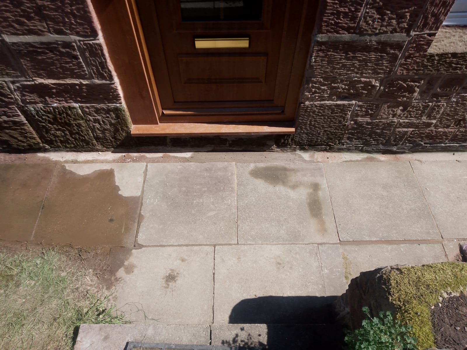 Reinstated flagged path outside the front door of a stone-built house following an underground drain repair