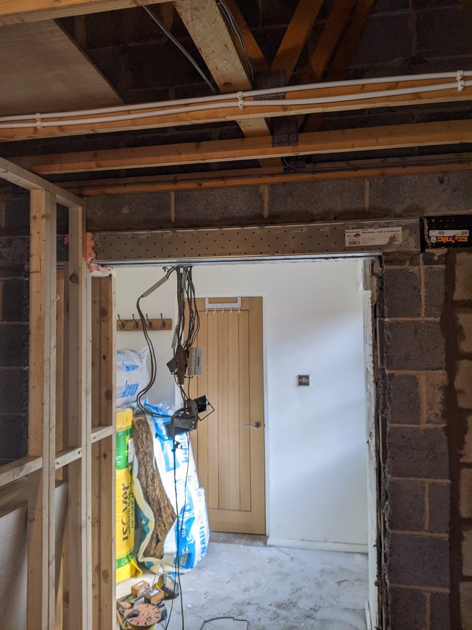 New steel beam installed over a structural opening formed between a garage and the hallway of a house