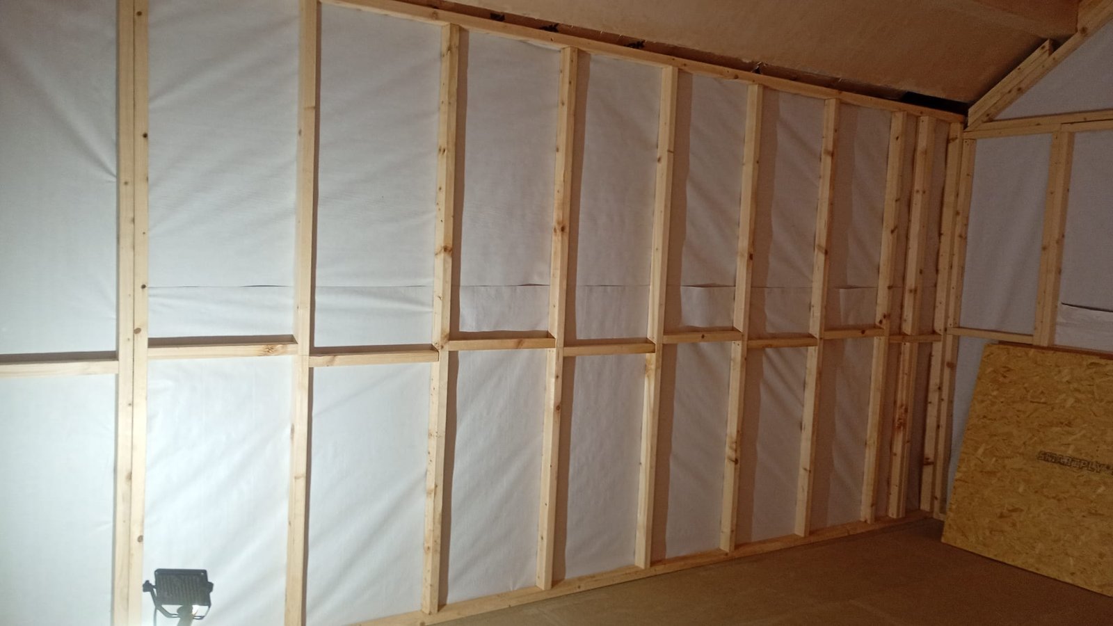 Timber stud wall framing with a breathable membrane fixed behind it during a garage conversion