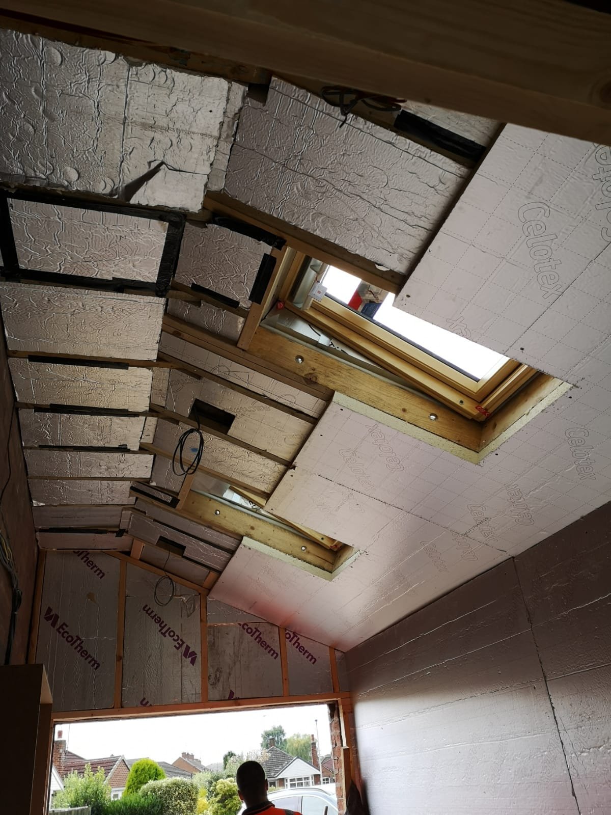 Rigid insulation boards fitted between and beneath roof rafters around two newly installed roof windows in a converted garage