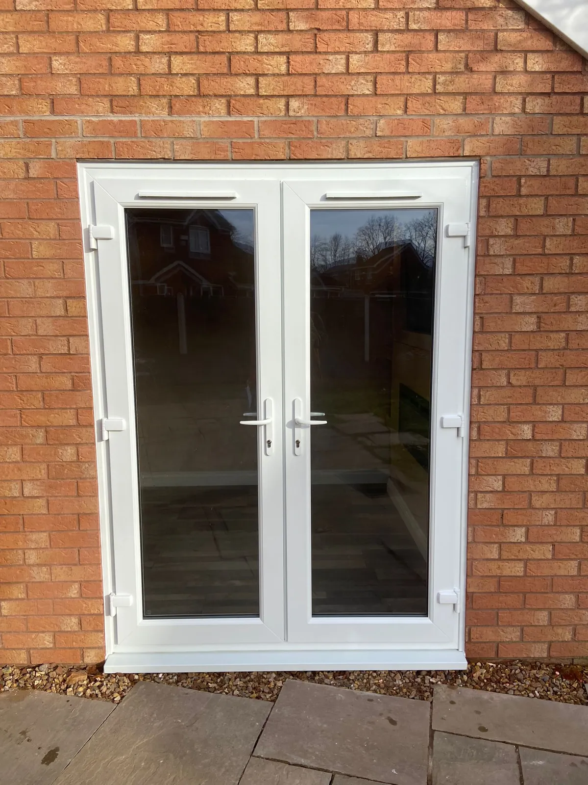 White uPVC French doors fitted in a new opening in the brick wall of a garage conversion