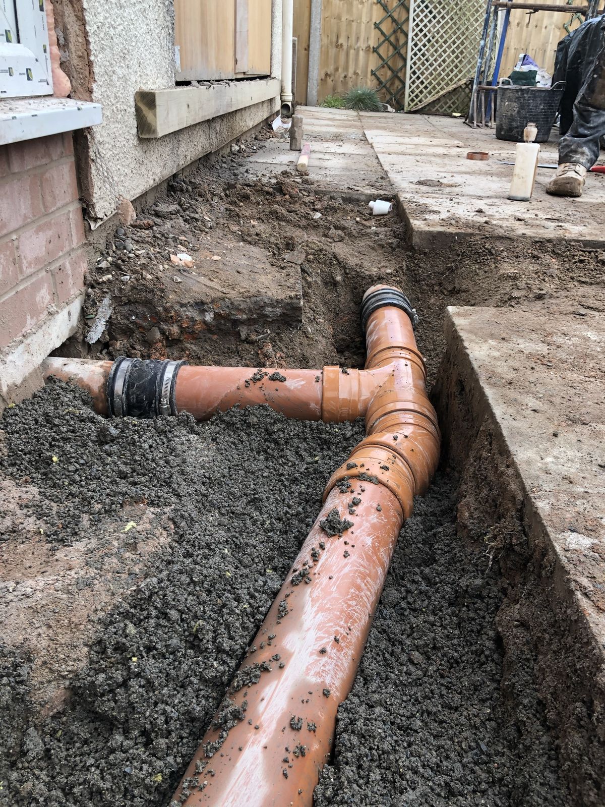 New plastic drain run joined to the old clay pipe with a flexible coupling, bedded in the trench
