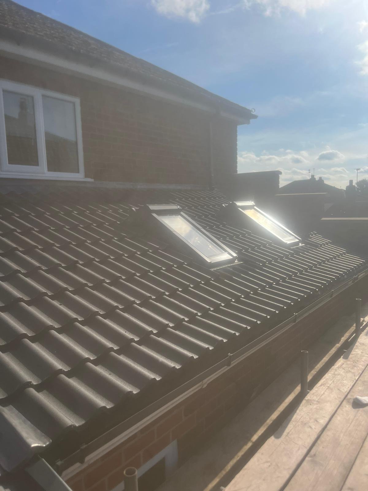 Newly tiled garage roof with two roof windows installed, seen from scaffolding