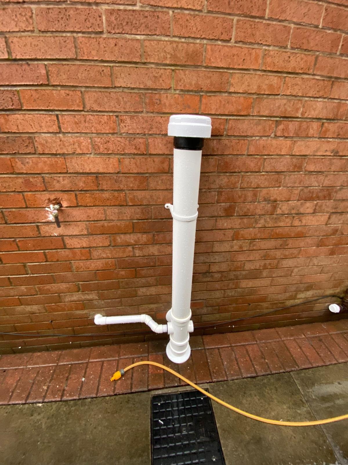 New white soil vent pipe installed against a brick wall to vent a newly installed drainage run