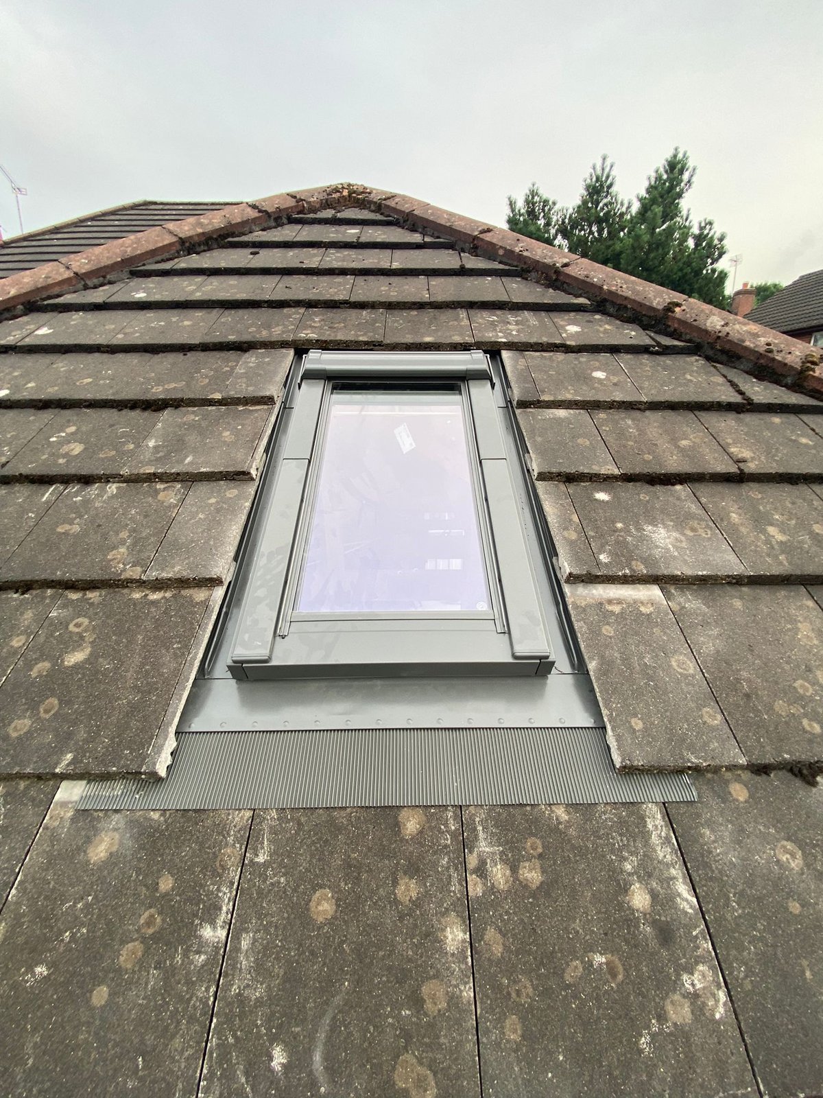 New roof light installed into a tiled roof slope with grey flashing kit