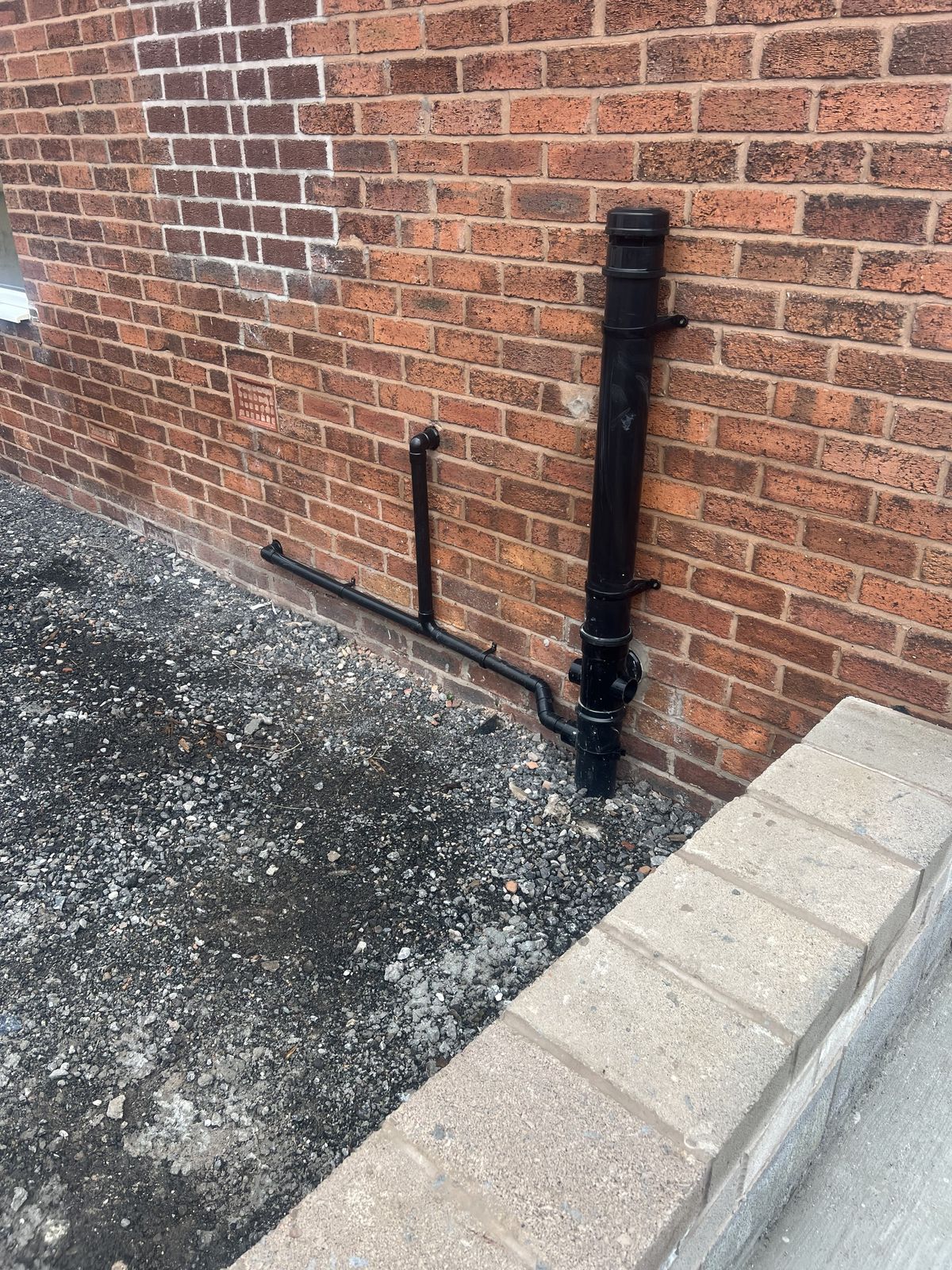 New external soil stack and waste pipework on a brick wall