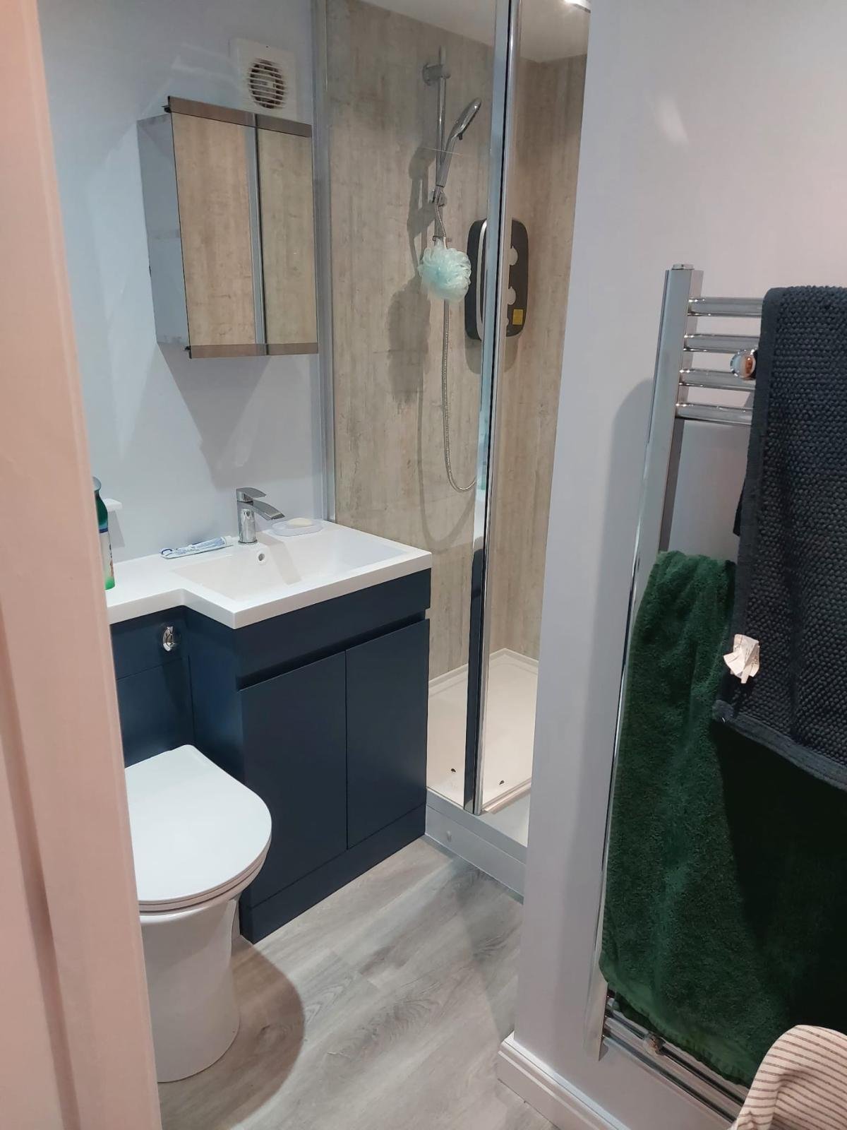 Finished shower room in a converted garage annexe with a shower enclosure, wall-hung basin unit, WC and heated towel rail