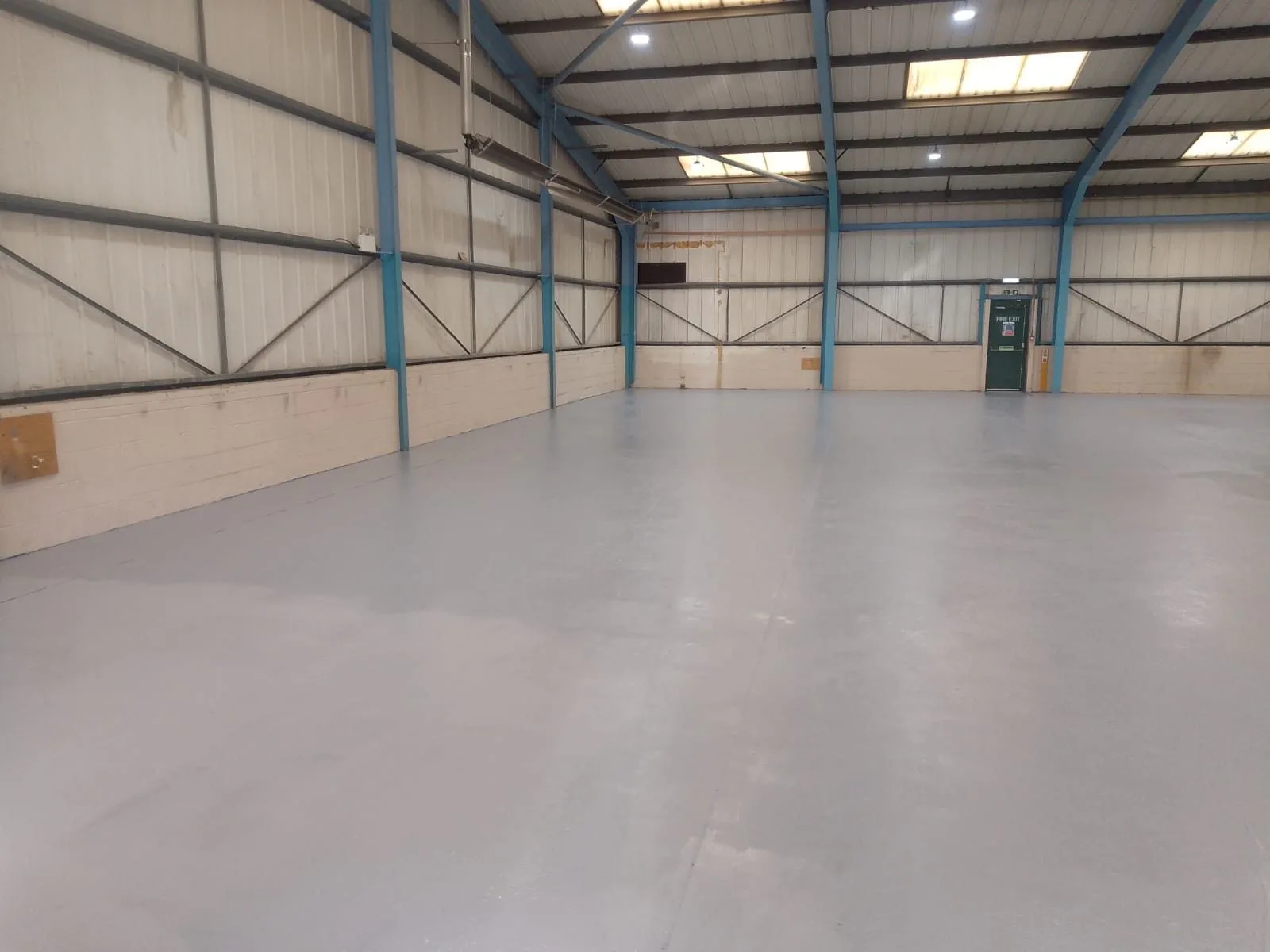 Warehouse floor freshly painted grey beneath a steel portal frame