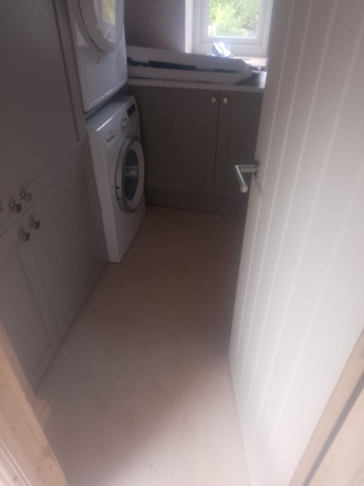 Finished utility room in a converted garage with fitted units, worktop, washing machine and stacked tumble dryer