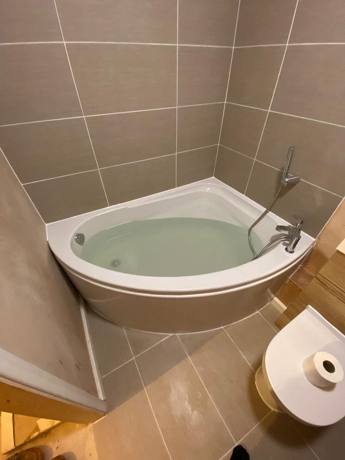 Corner bath installed and tiled in a bathroom created within a converted garage