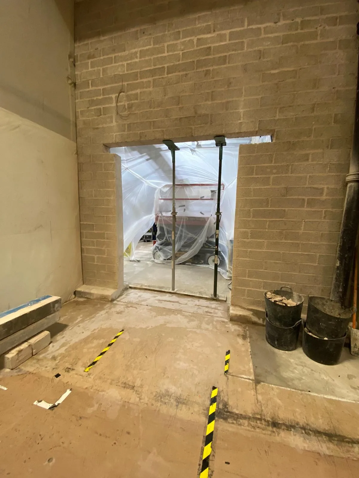 New structural opening formed through a blockwork wall in a commercial unit, temporarily propped