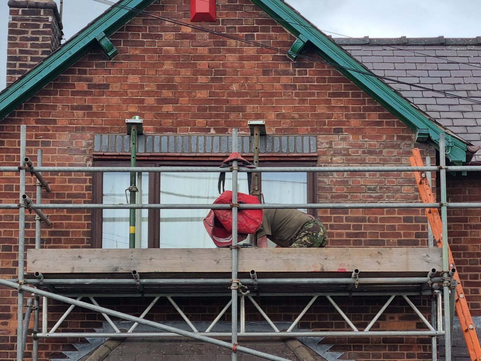 Brickwork propped above a window head Props supporting the brickwork above a window with a blue brick soldier course over the opening, and an operative working on the scaffold