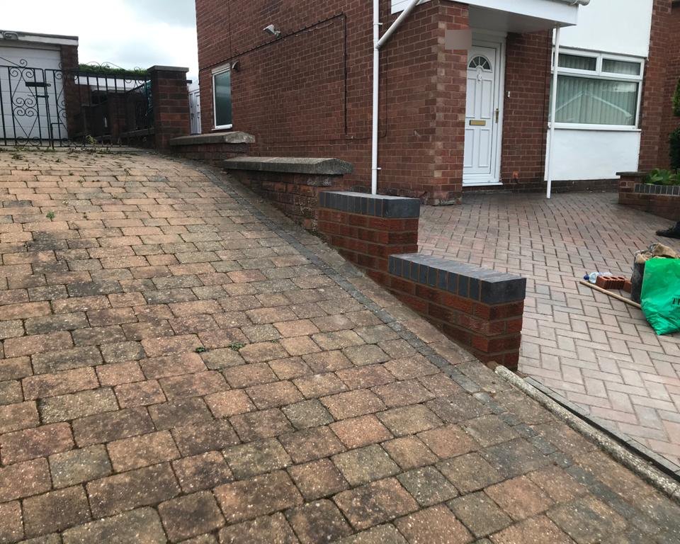 Low brick garden wall rebuilt beside a block-paved drive with a blue brick coping and a new pier at the end