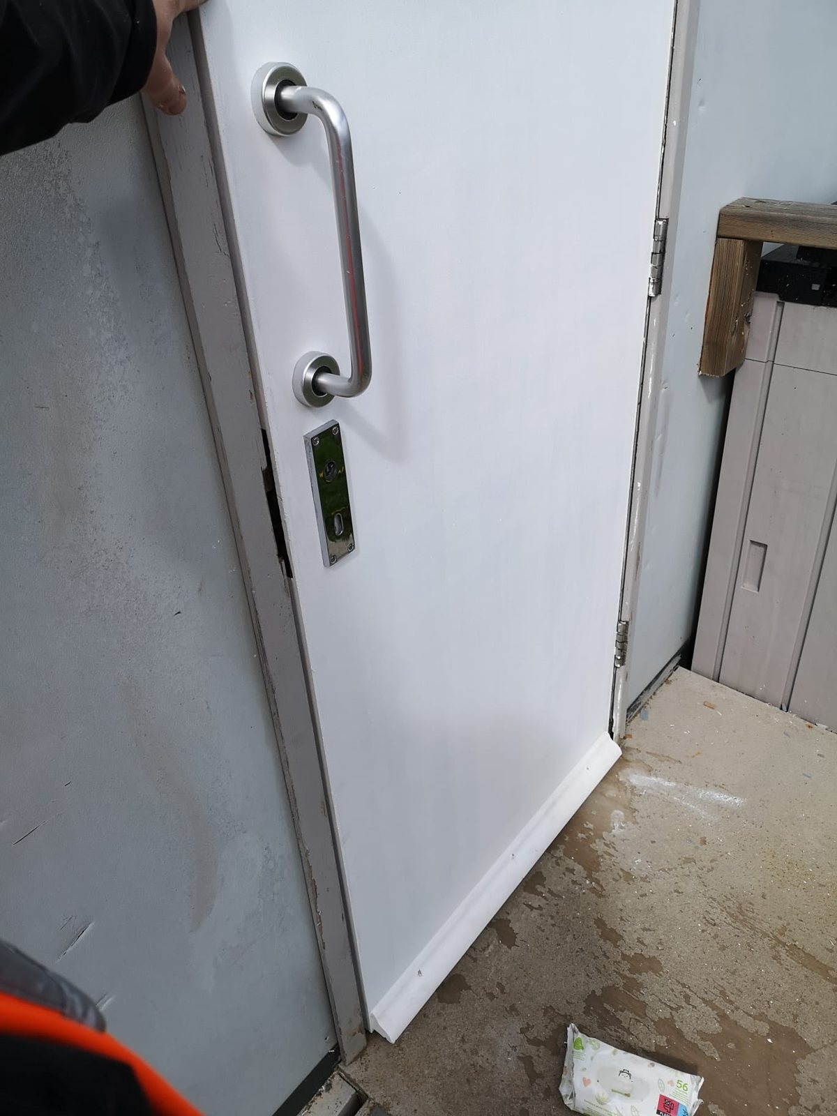 Operative steadying a commercial door by hand during a repair