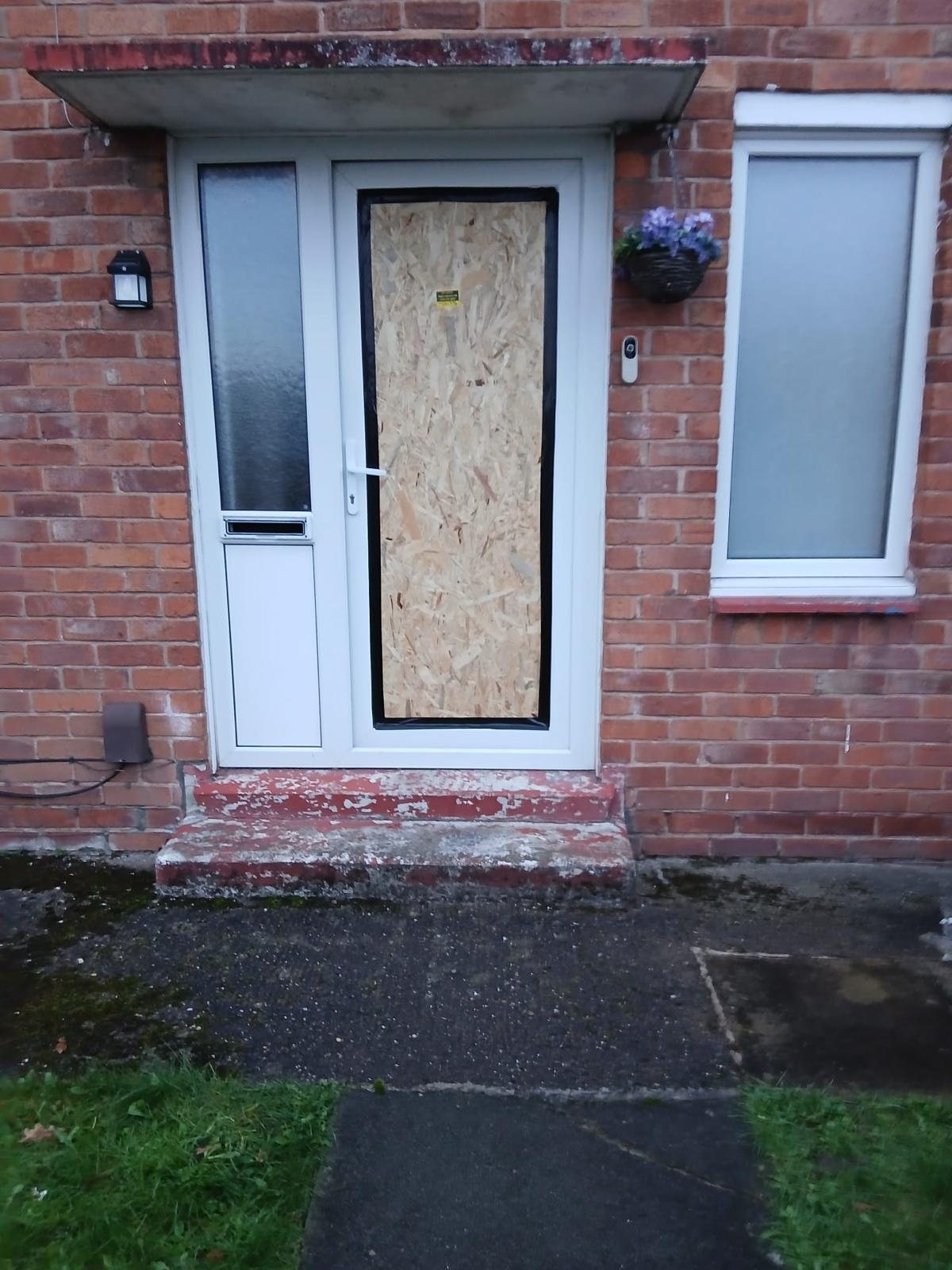 uPVC front door with its glazed panel boarded over in OSB, taped at the edges