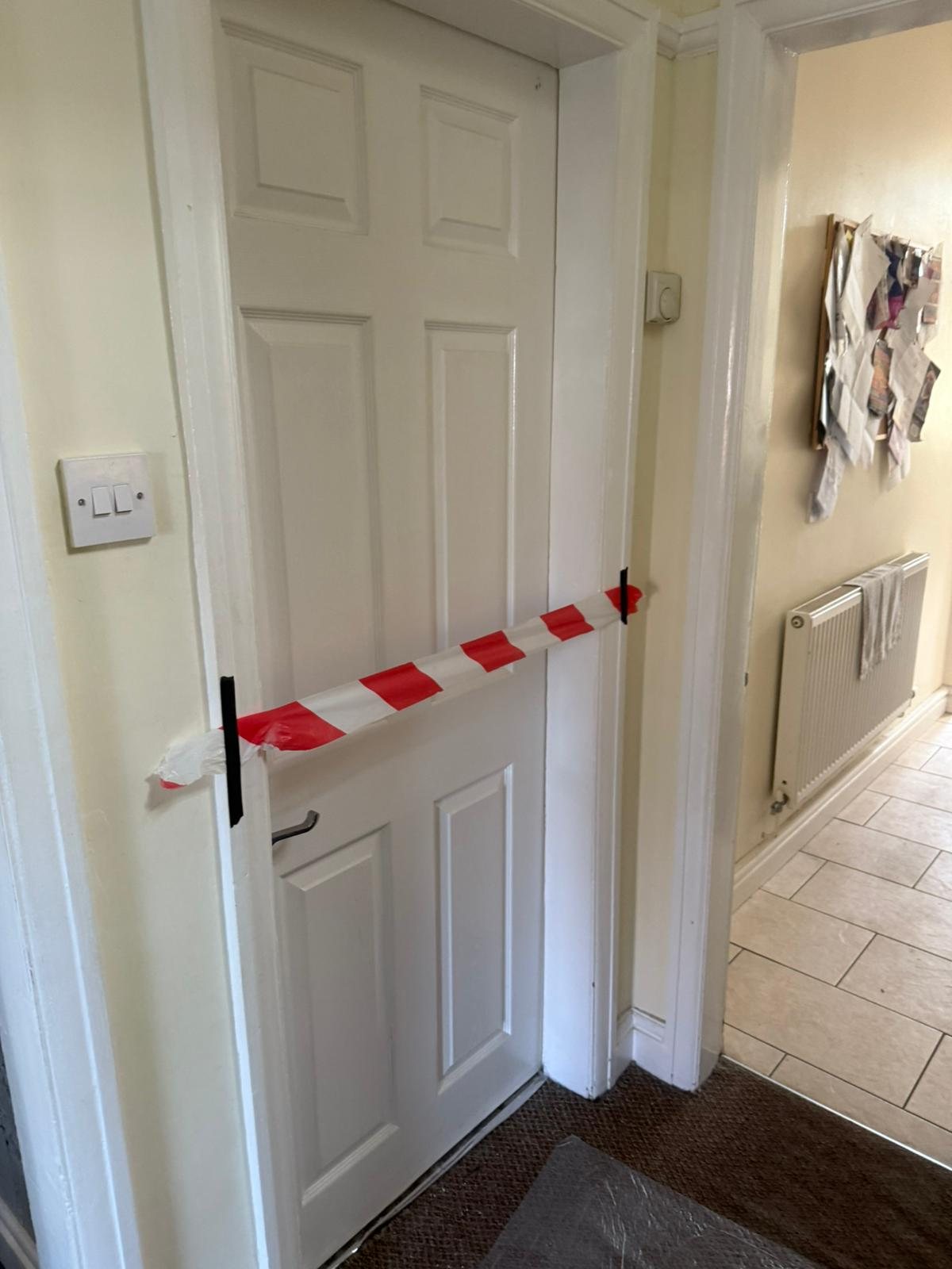 White panelled door taped shut with red and white barrier tape