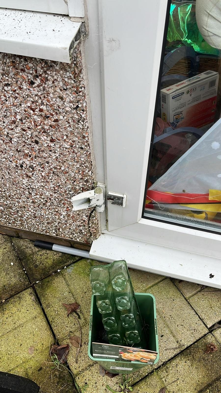 Broken flag hinge at the foot of a uPVC door, sheared away from the frame