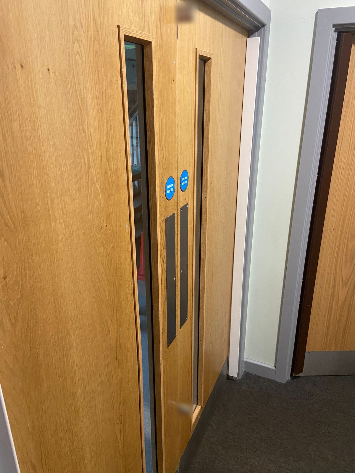 Pair of oak-veneered fire doors with vision panels, push plates and Fire door keep shut signs