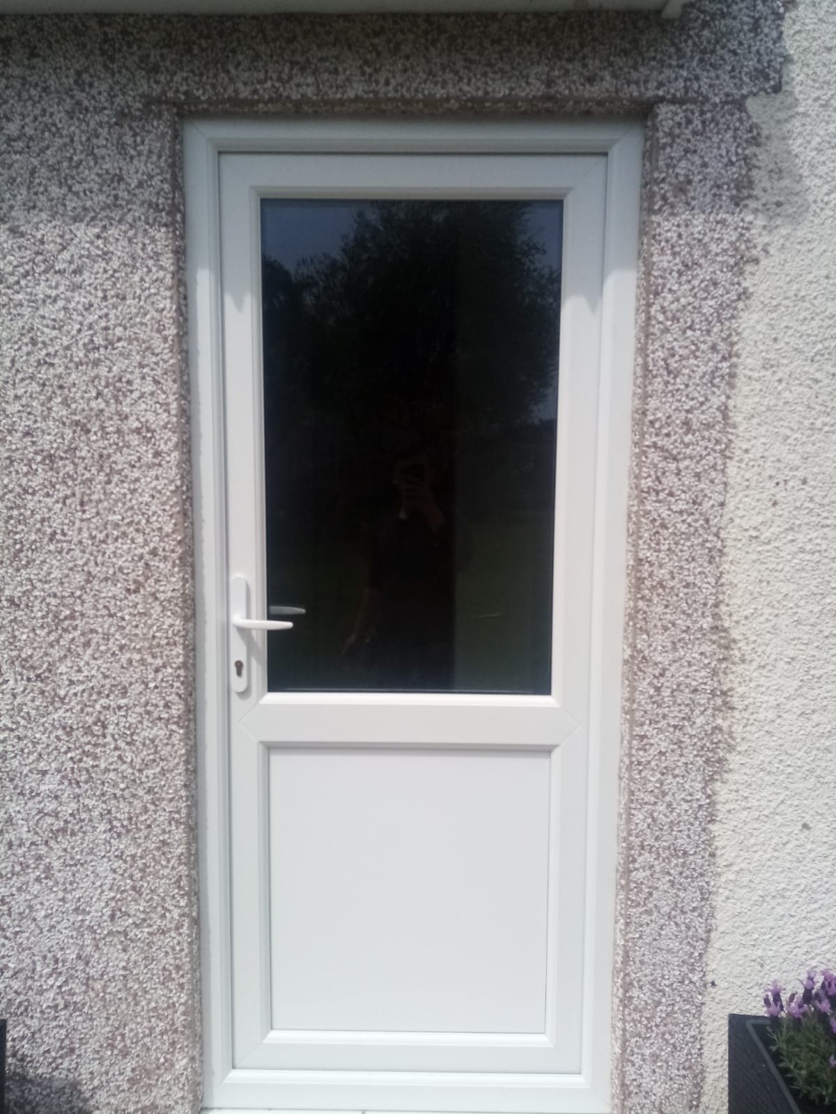 White uPVC back door with a half-glazed panel in a pebbledashed wall