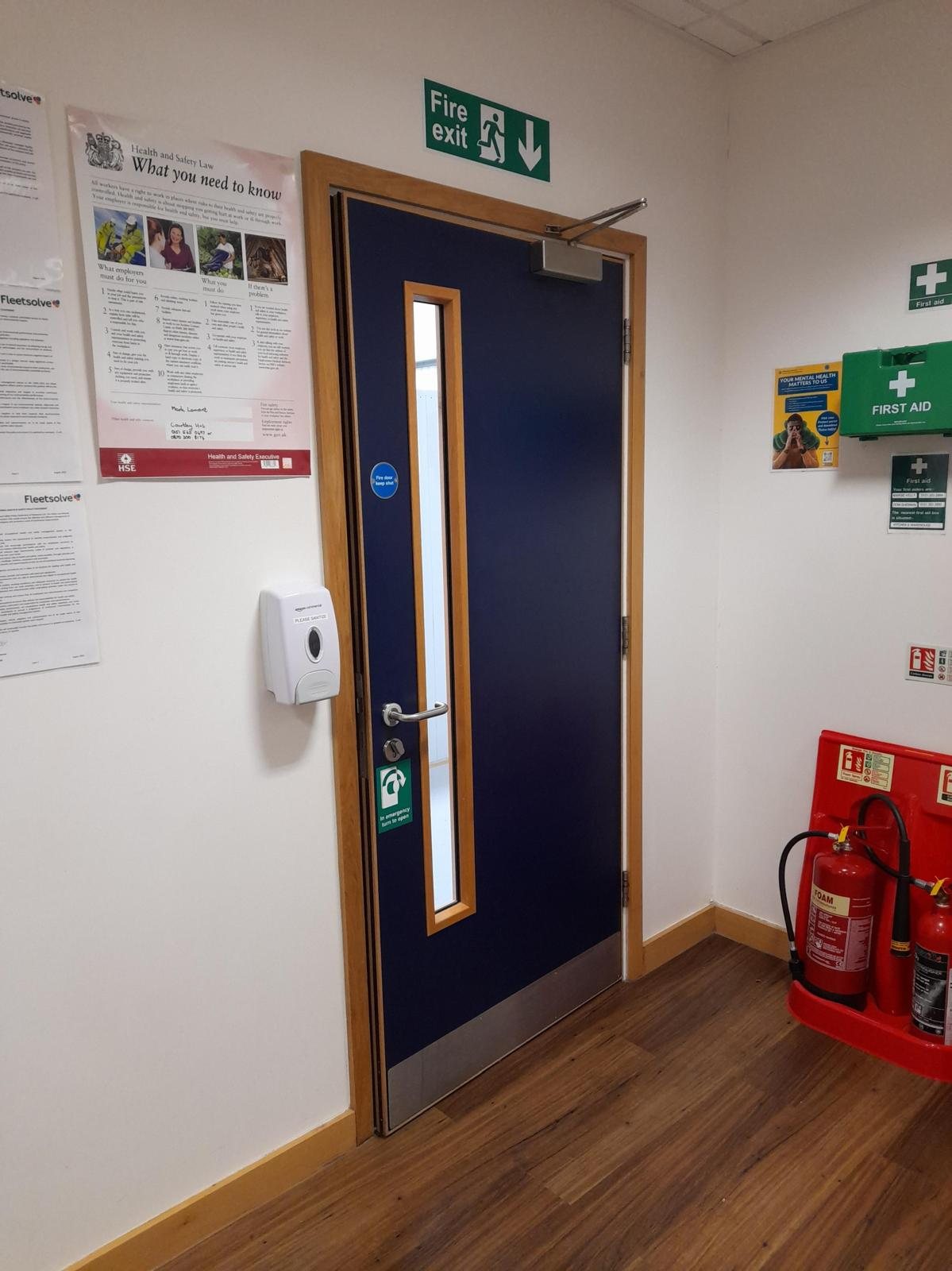 Blue fire door with an overhead closer, vision panel and kick plate