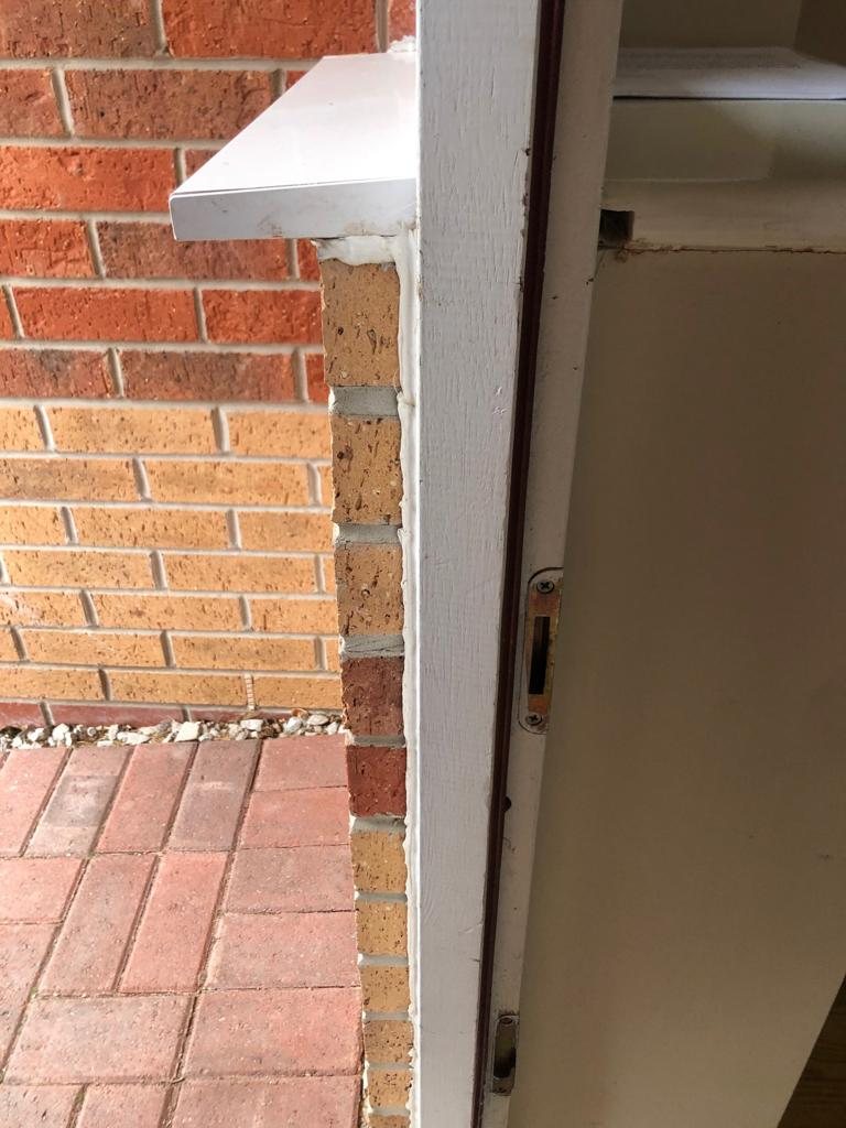 Keep and latch plate on the frame of an external door, seen edge-on by the brick reveal