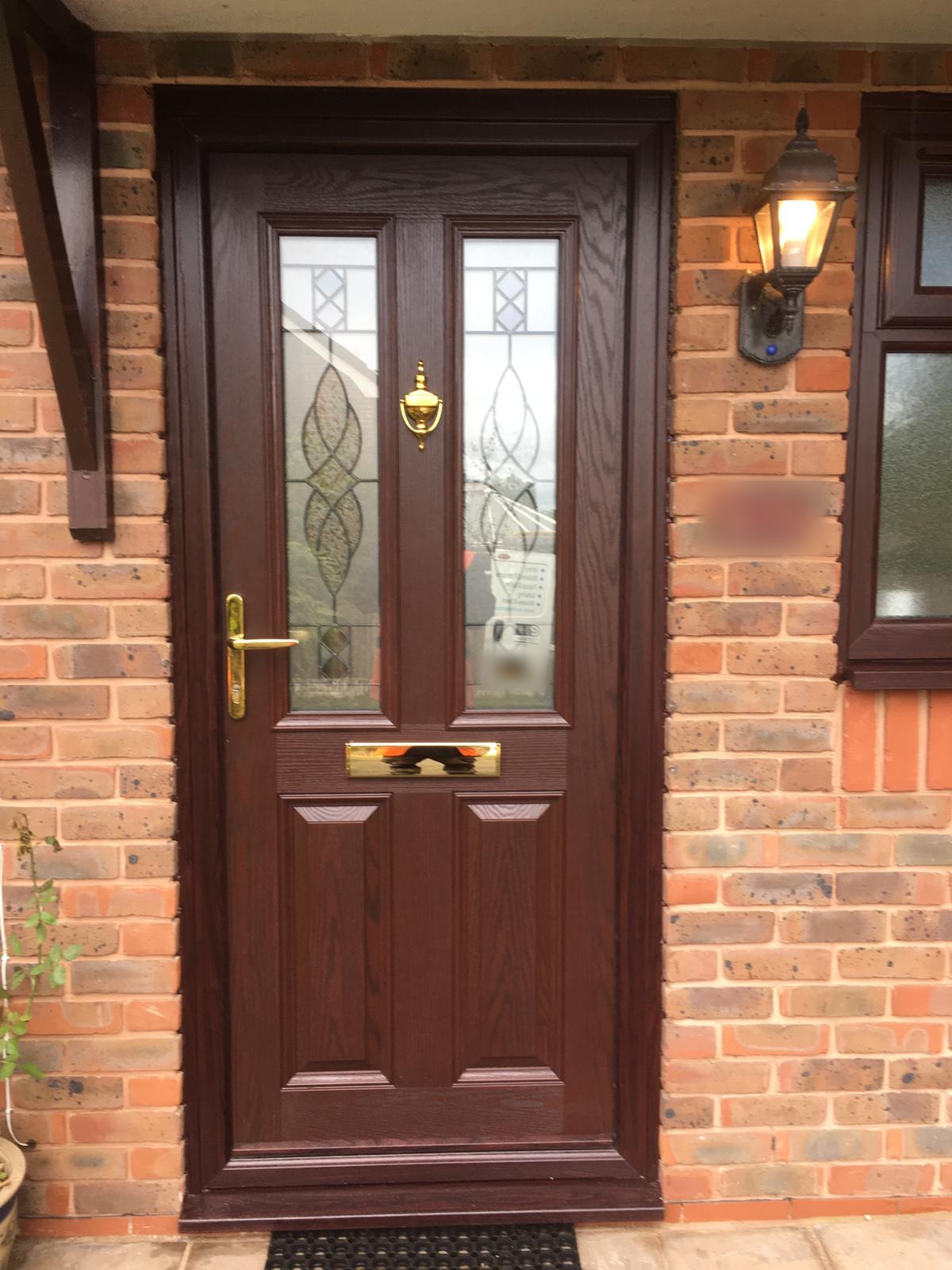 Rosewood composite front door with decorative glazed panels, a brass handle, letter plate and knocker