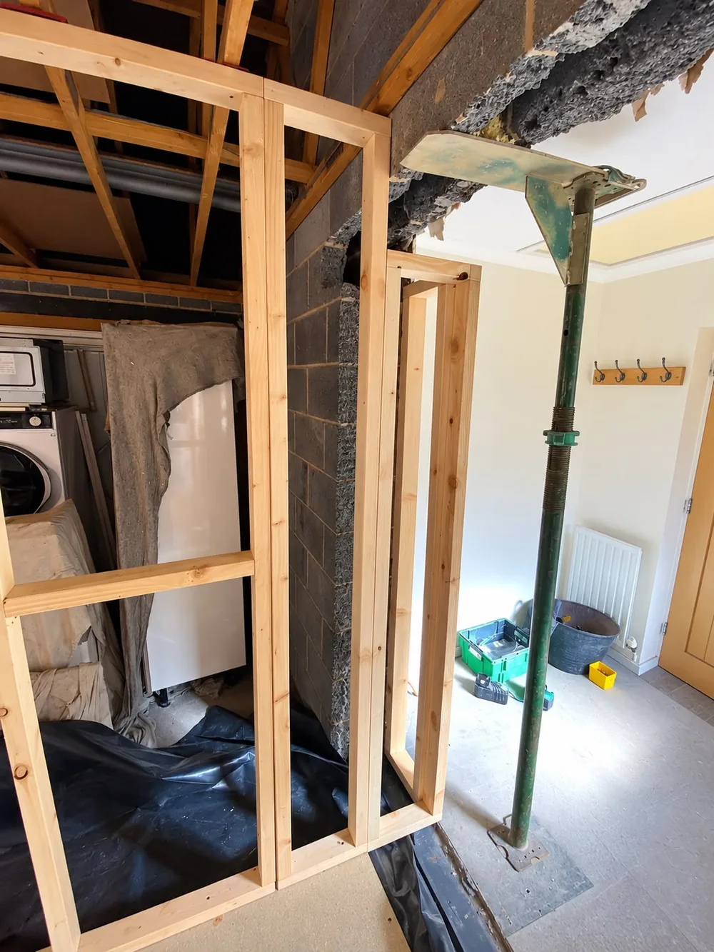 New opening formed from the garage into the house, timber studwork in place and an adjustable prop supporting the structure above