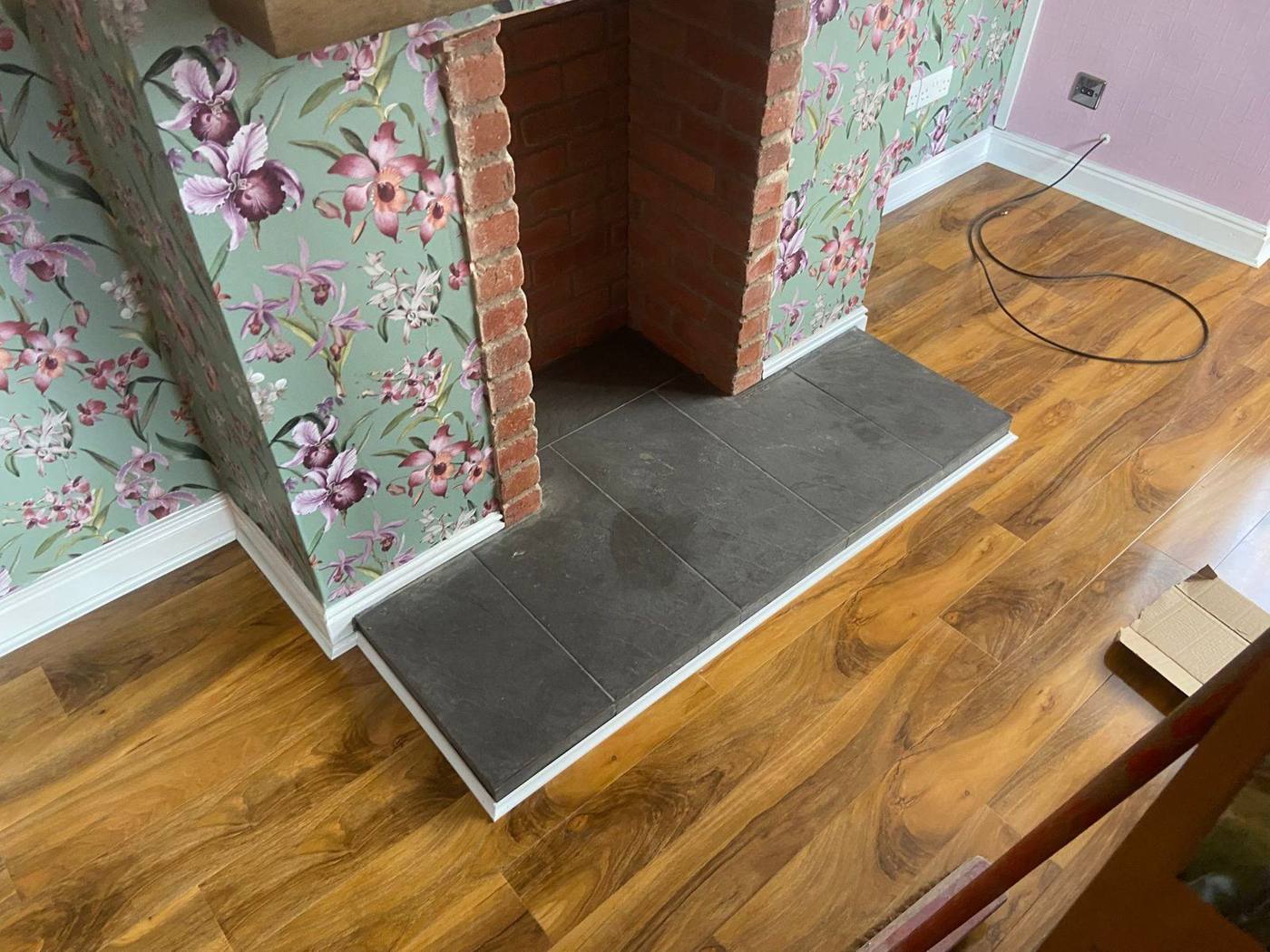 Opened-up fireplace with a slate hearth Opened-up fireplace with a brick-lined chamber and a slate hearth, in a wallpapered chimney breast