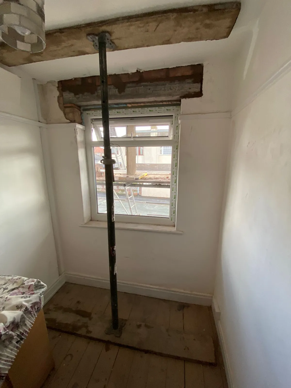Adjustable steel prop in a bedroom holding a timber beam above the window