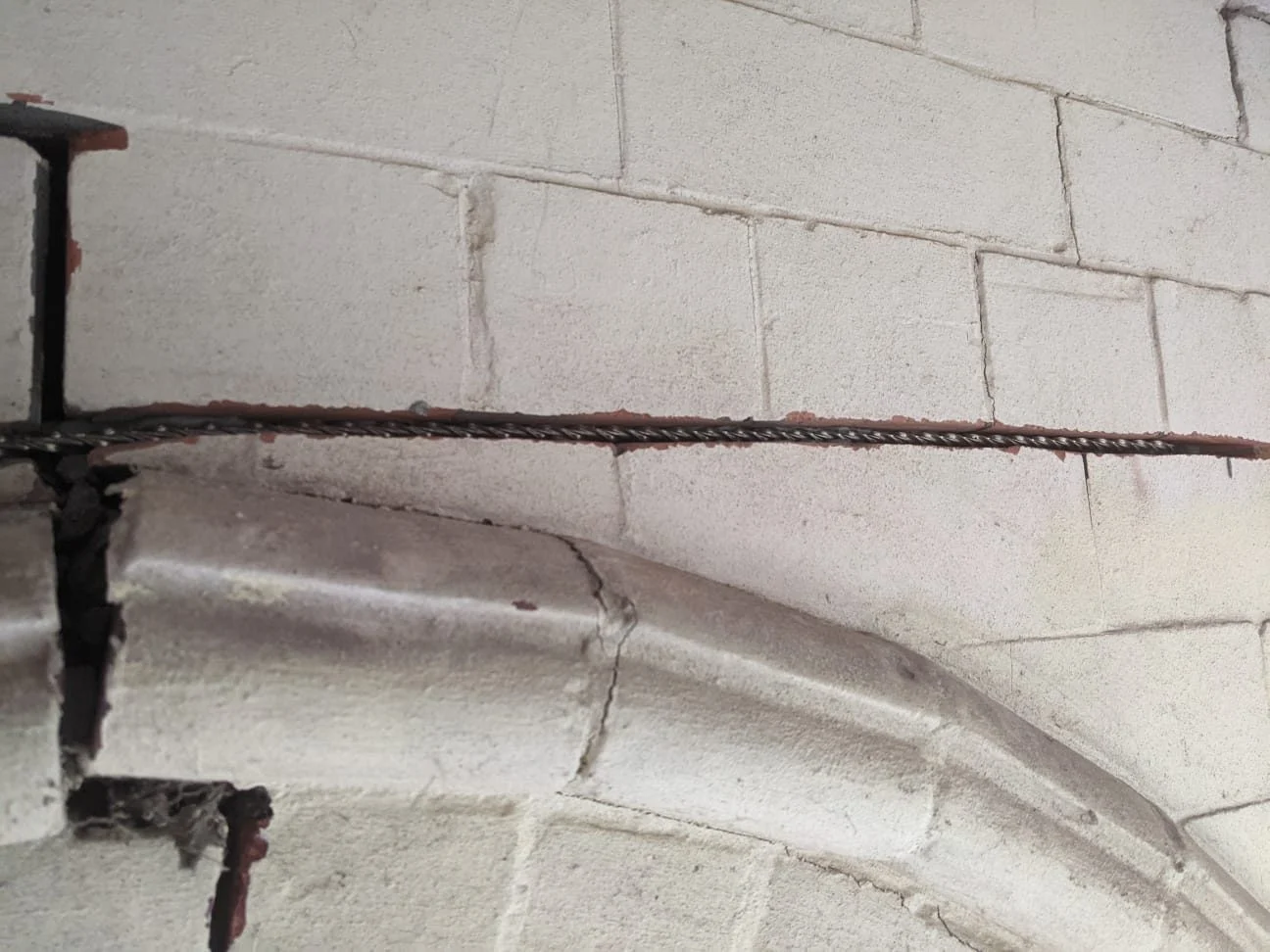 Helical bar bedded into a raked-out bed joint above an arched opening during crack stitching by Quirks Property Maintenance