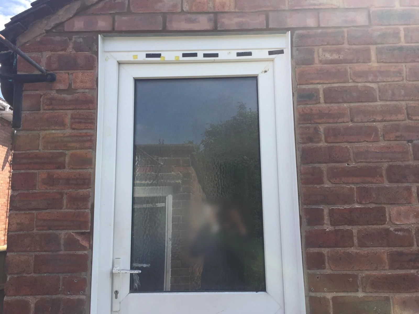 White glazed door in a brick wall with rebuilt, repointed brickwork above the frame