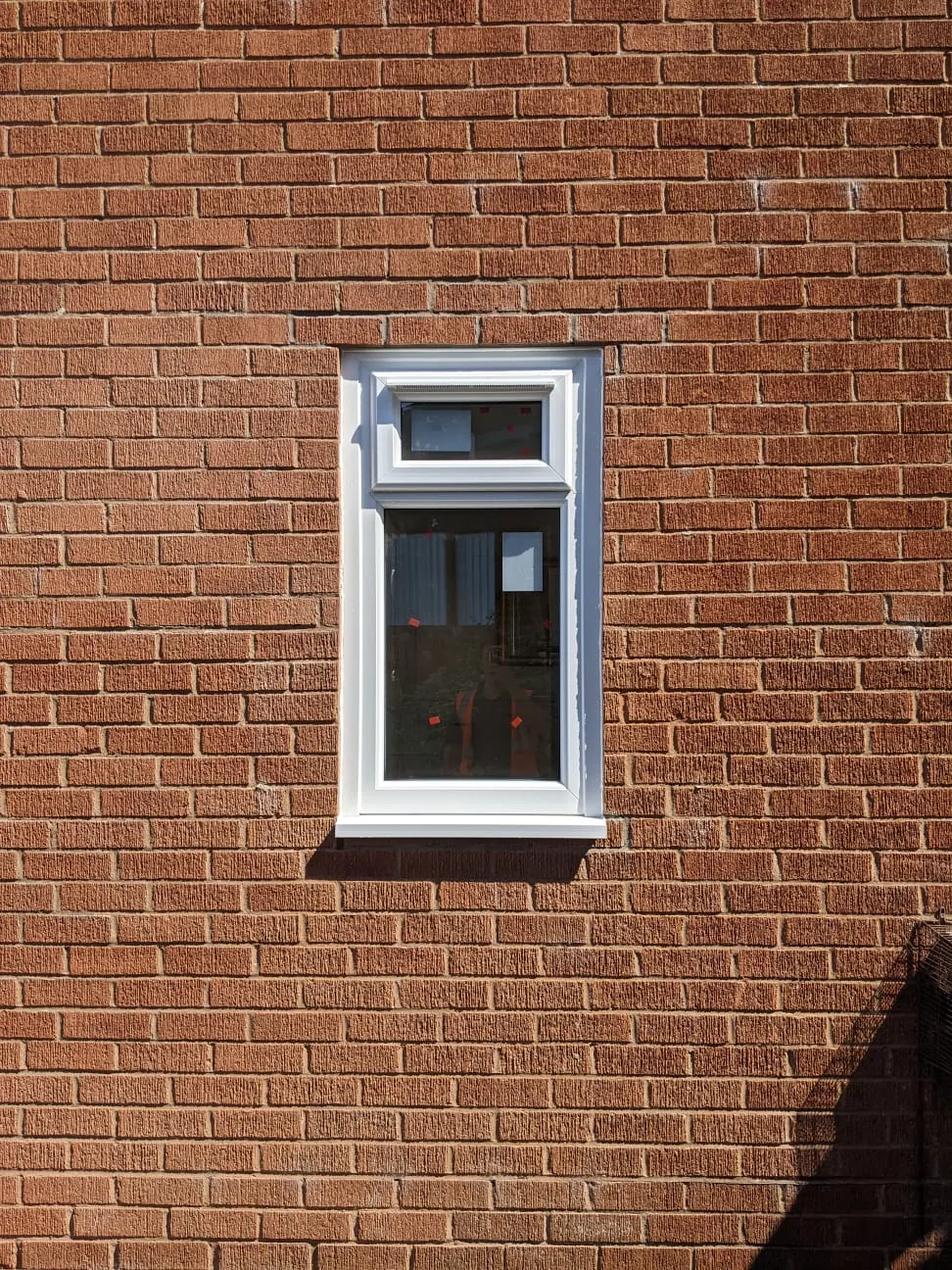 New white uPVC window fitted in a red brick wall with the brickwork closed neatly above it