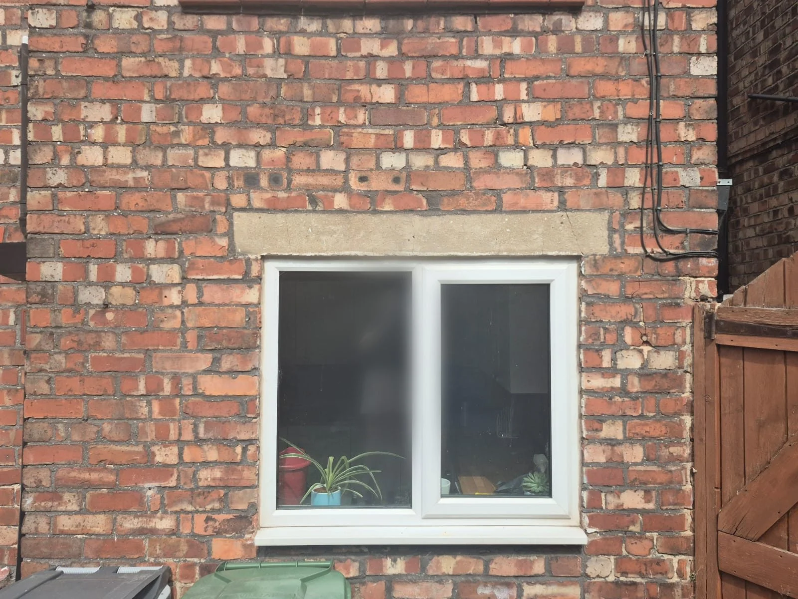 Cracked concrete lintel over a rear kitchen window with cracking stepping up through the mortar joints in the brickwork above