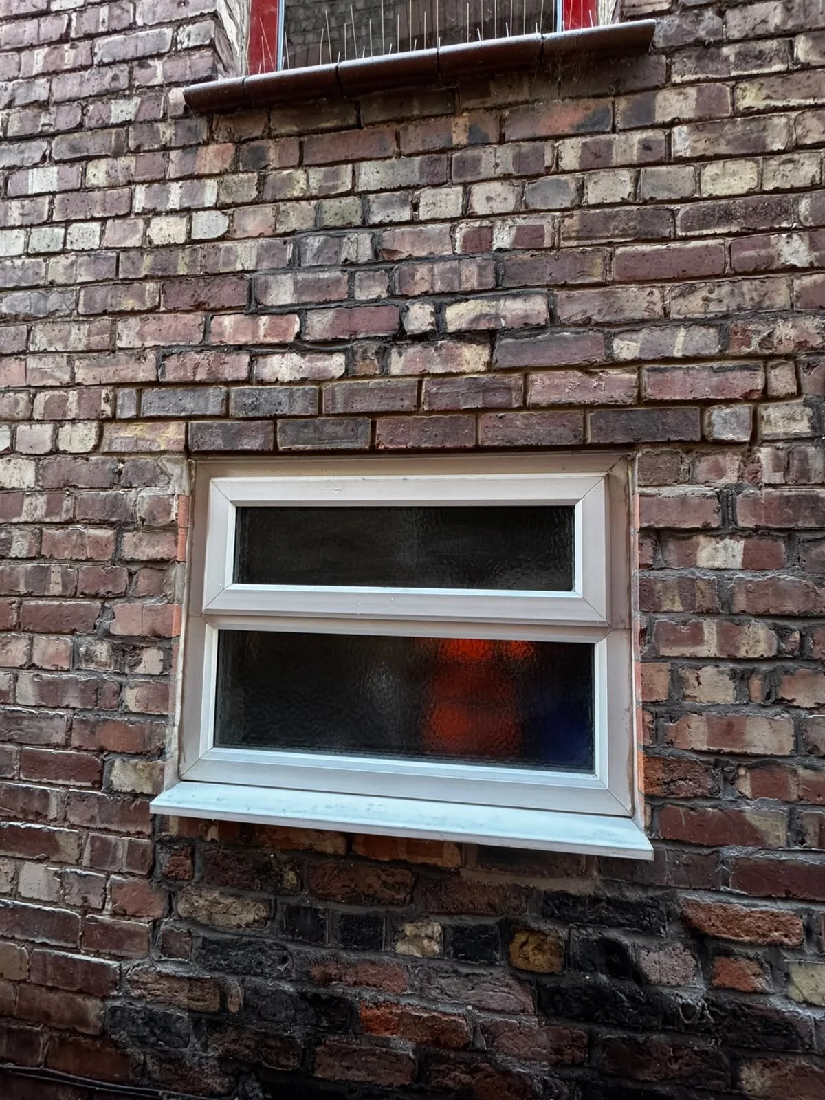 Passageway window in an end-of-terrace house with a new single-leaf lintel and the brickwork above the window head made good