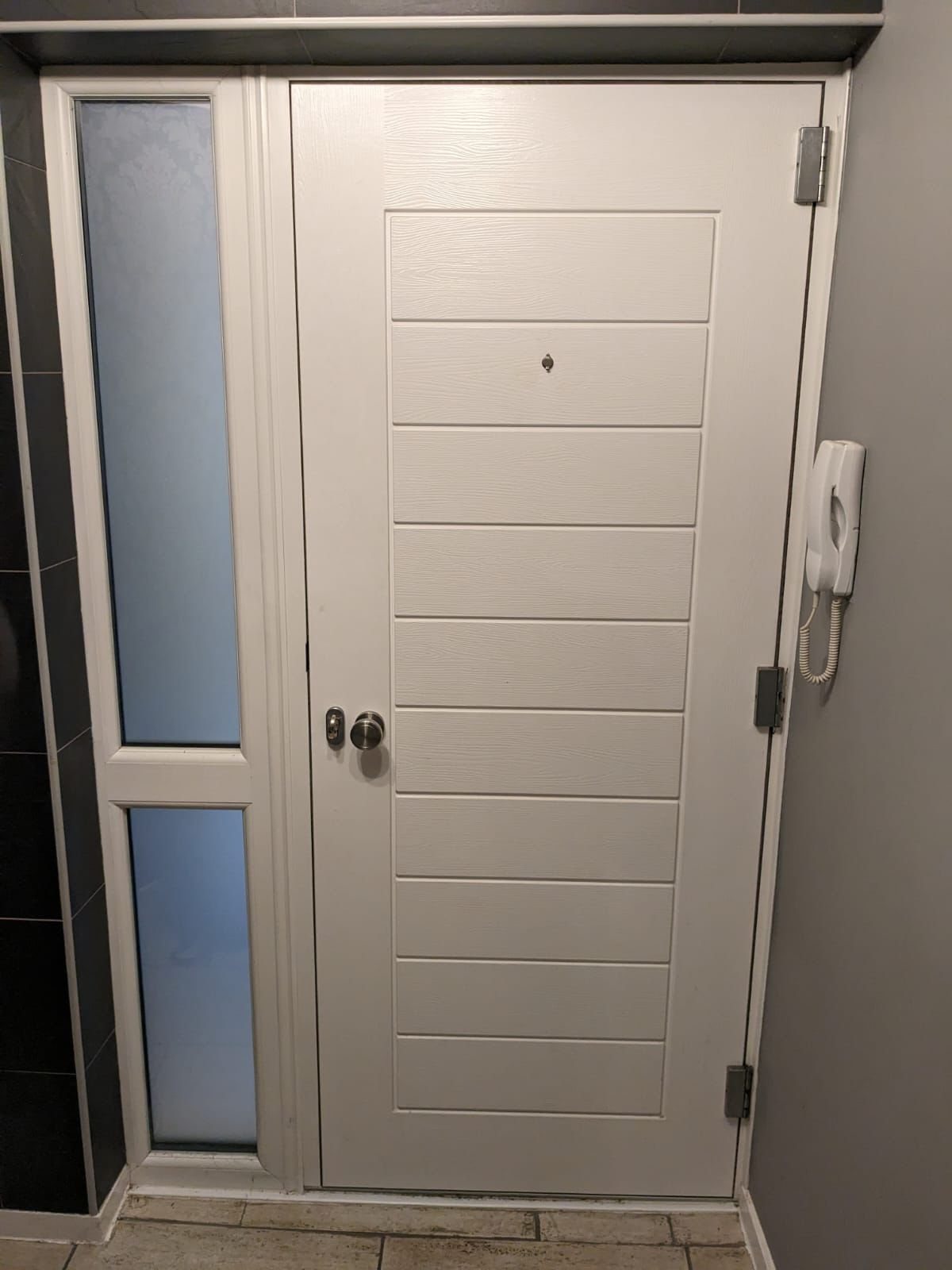 Composite entrance door to a flat, closed and secure in its frame
